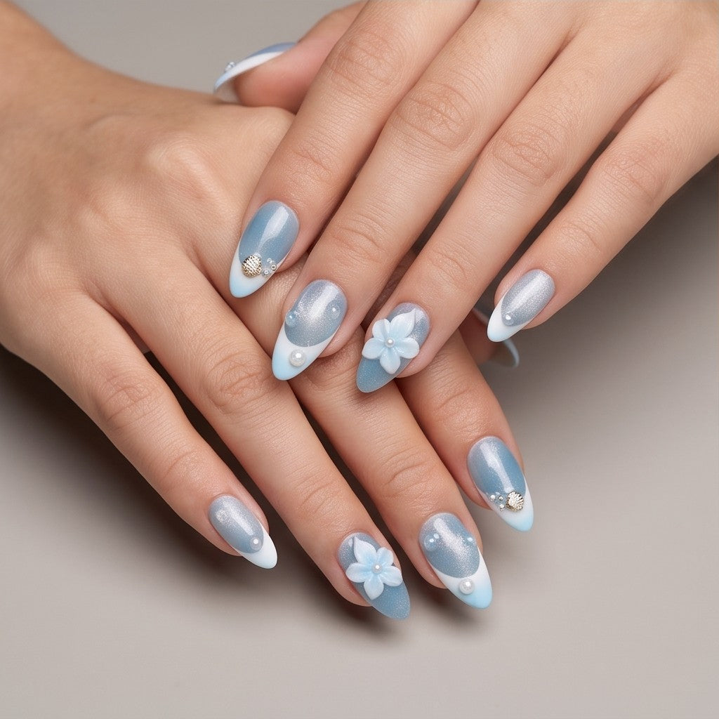 Ocean Mist – shimmer blue French tip almond press-on nails with a 3D flower and seashell charm worn on hand