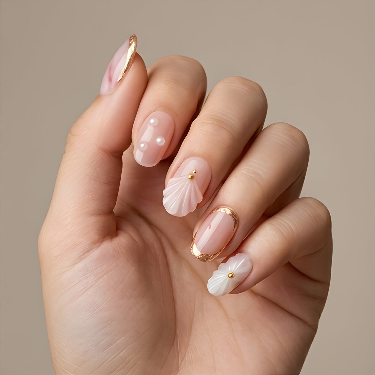 Blush Seashell – blush pink short oval press-on nails with 3D seashells, pearls and gold foil worn on hand