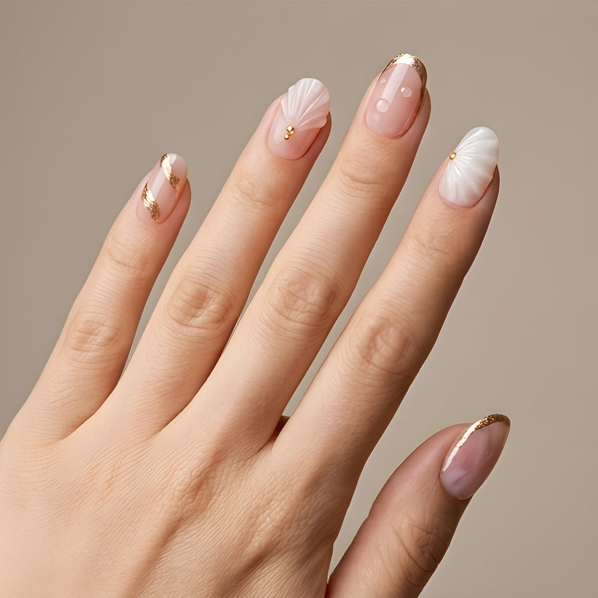 Blush Seashell – blush pink short oval press-on nails with 3D seashells, pearls and gold foil worn on hand