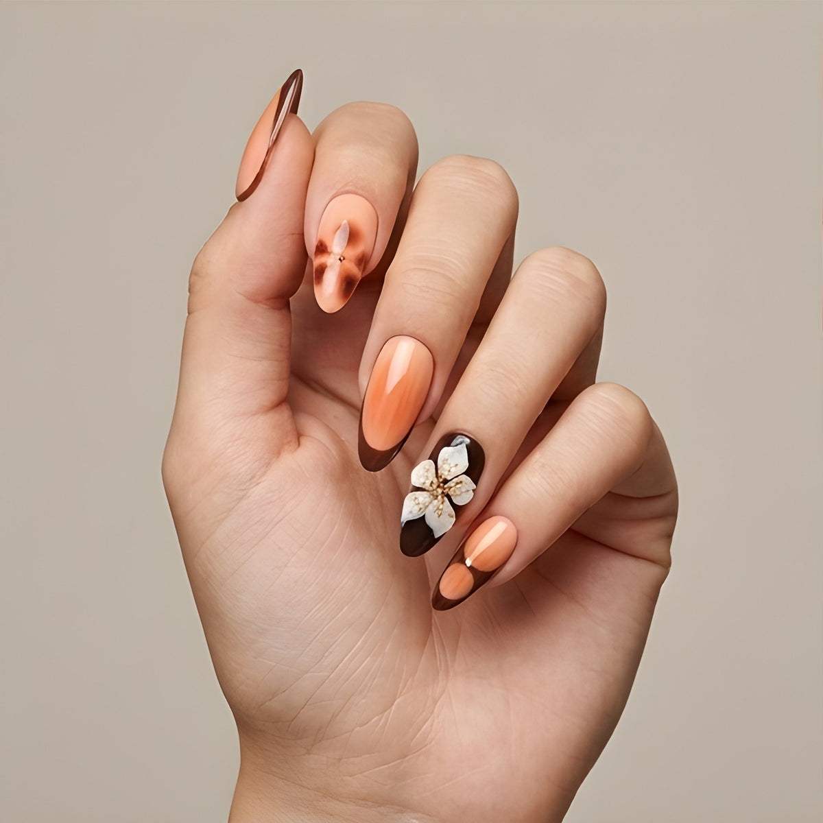 Peach Cocoa – peach and chocolate French tip almond press-on nails with 3D flowers worn on hand