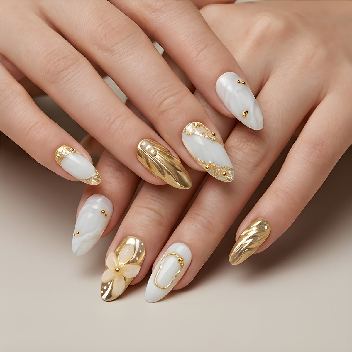 Gilded Pearl – marble white and gold chrome almond press-on nails with 3D flowers worn on hand